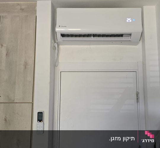 מזגן מותקן על קיר עם שלט רחוק תלוי